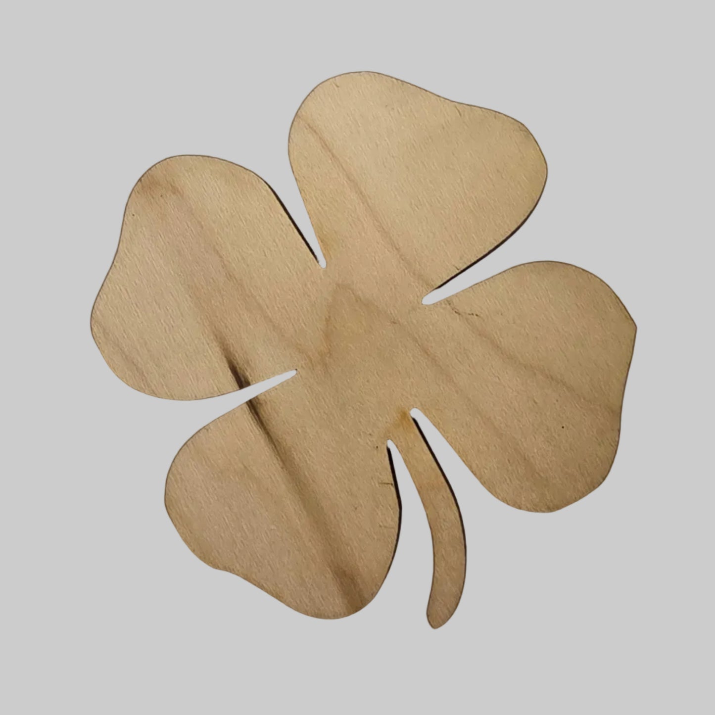Wooden four-leaf clover cutout on a light gray background