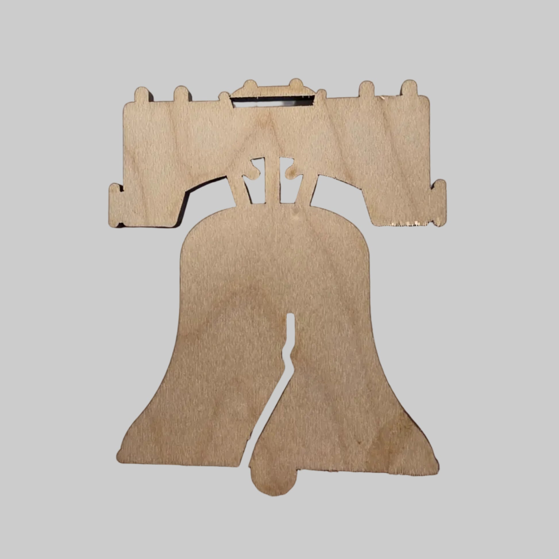 Wooden liberty bell-shaped object on a light gray background