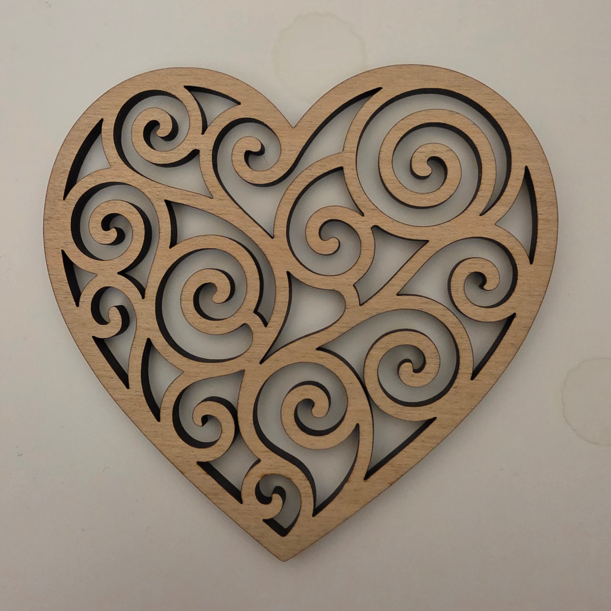 Decorative wooden heart with intricate spiral patterns on a plain background