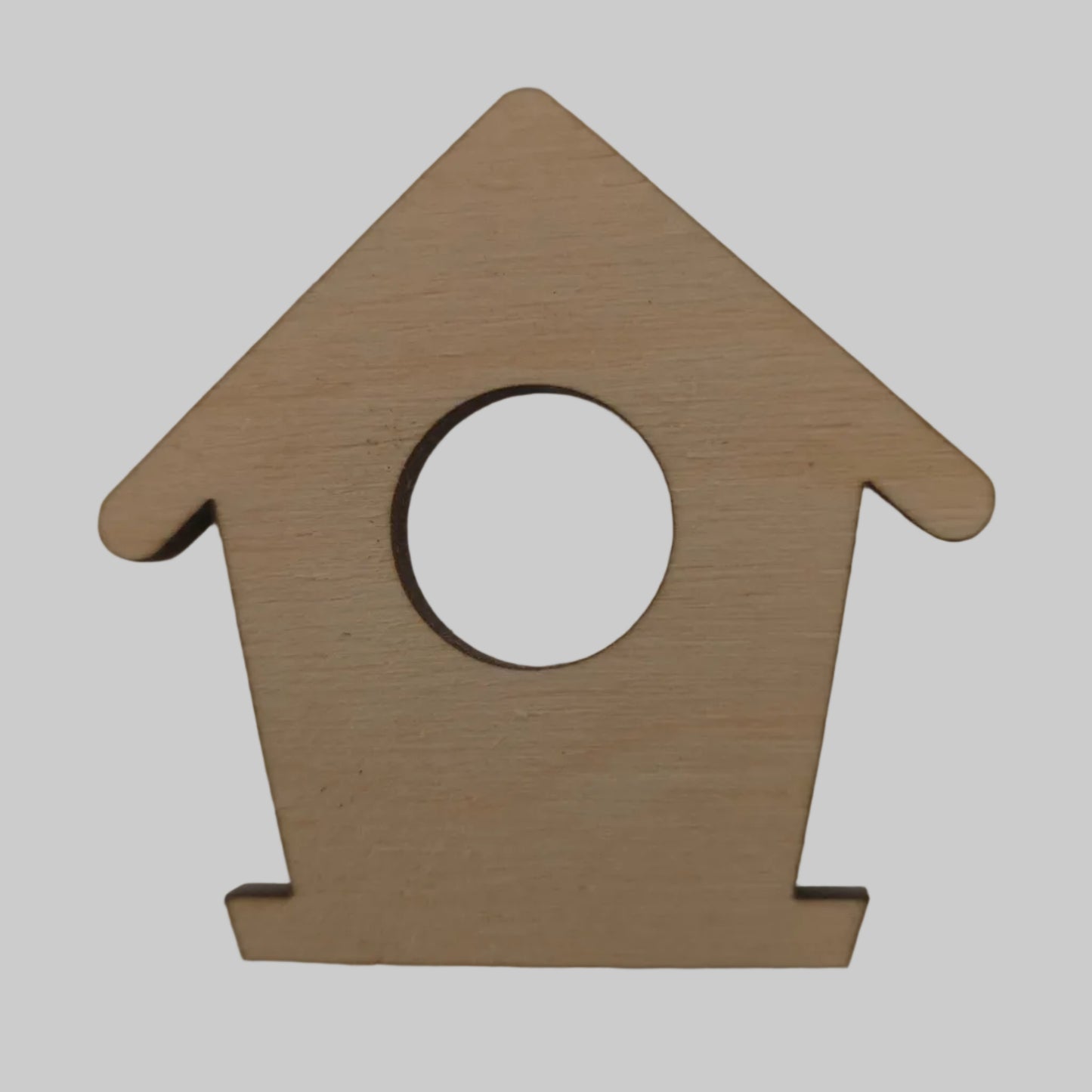 Wooden bird house-shaped object with a circular center on a beige background