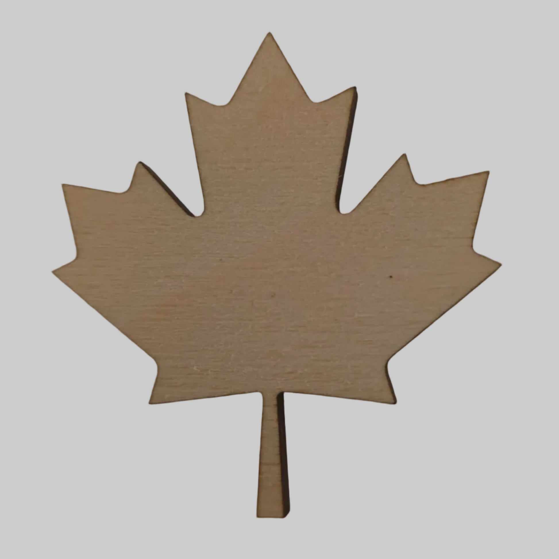 Wooden maple leaf-shaped cutout on a beige background