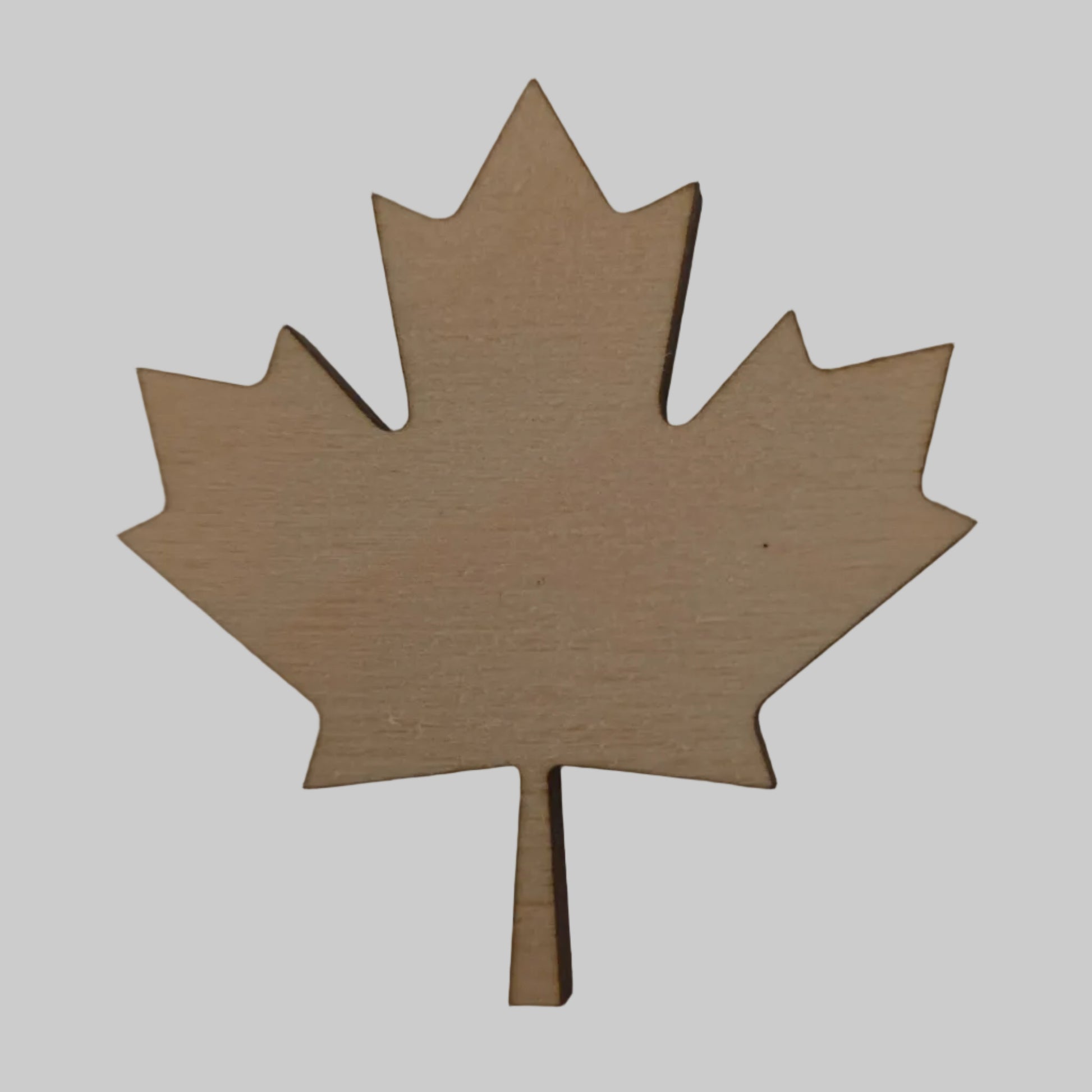 Wooden maple leaf-shaped cutout on a beige background