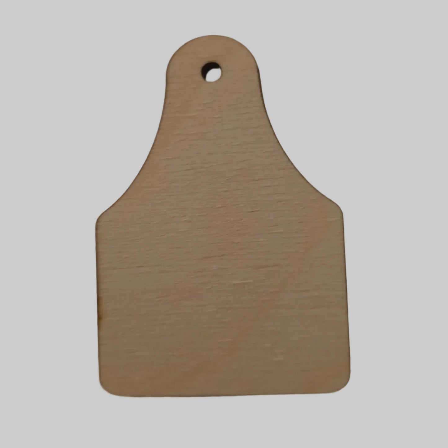 Laser cut wood cattle ear tag on a beige background