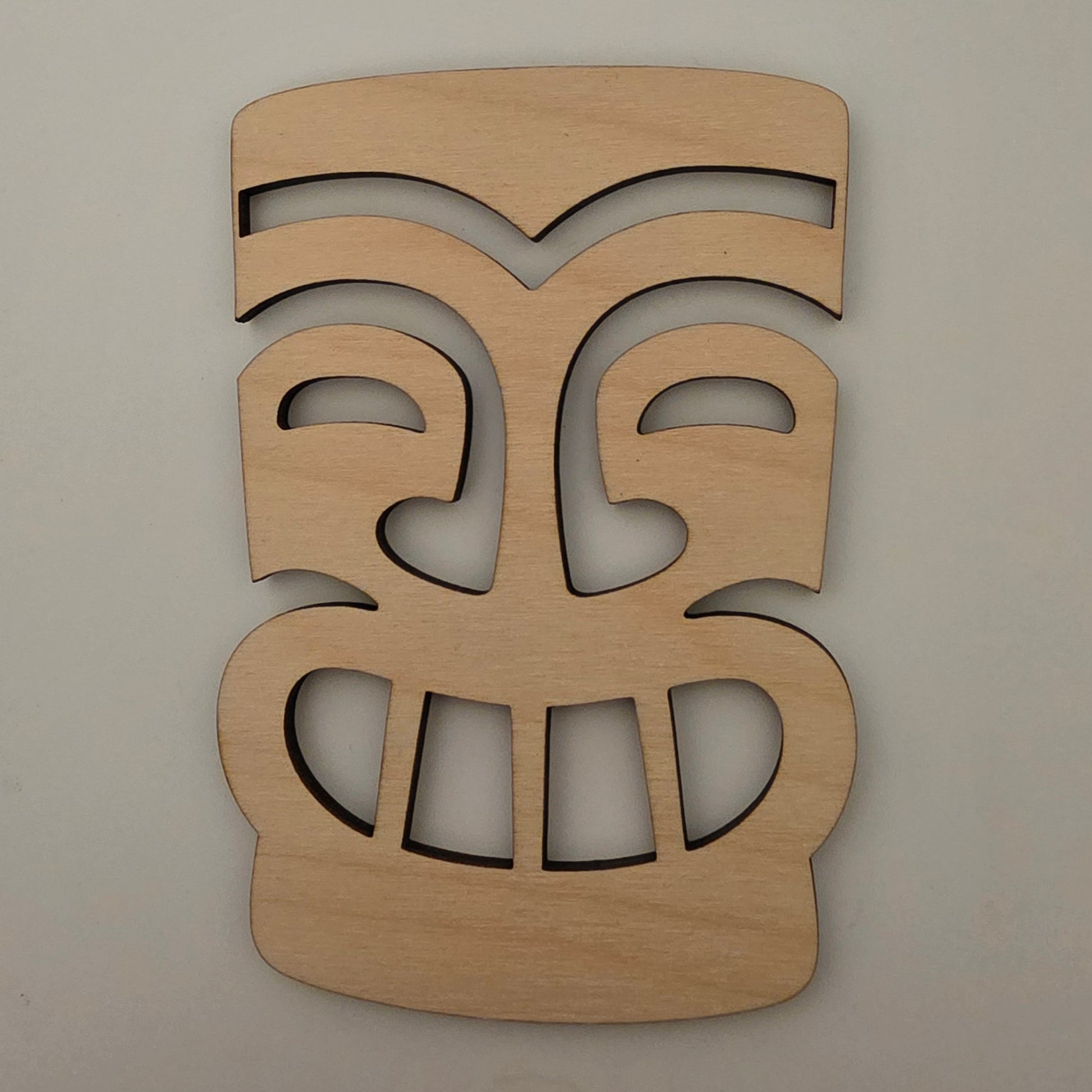 Wooden tiki mask cut-out design on a plain background